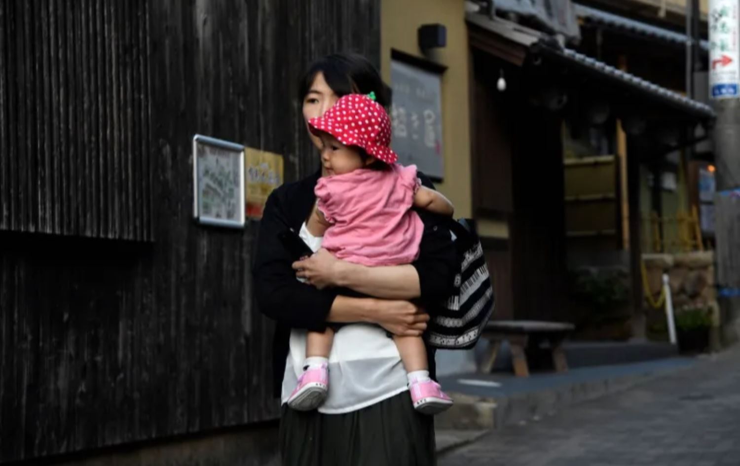 دایکێکی یابانییە منداڵەکەی هەڵگرتووە. وێنەکە: AFP