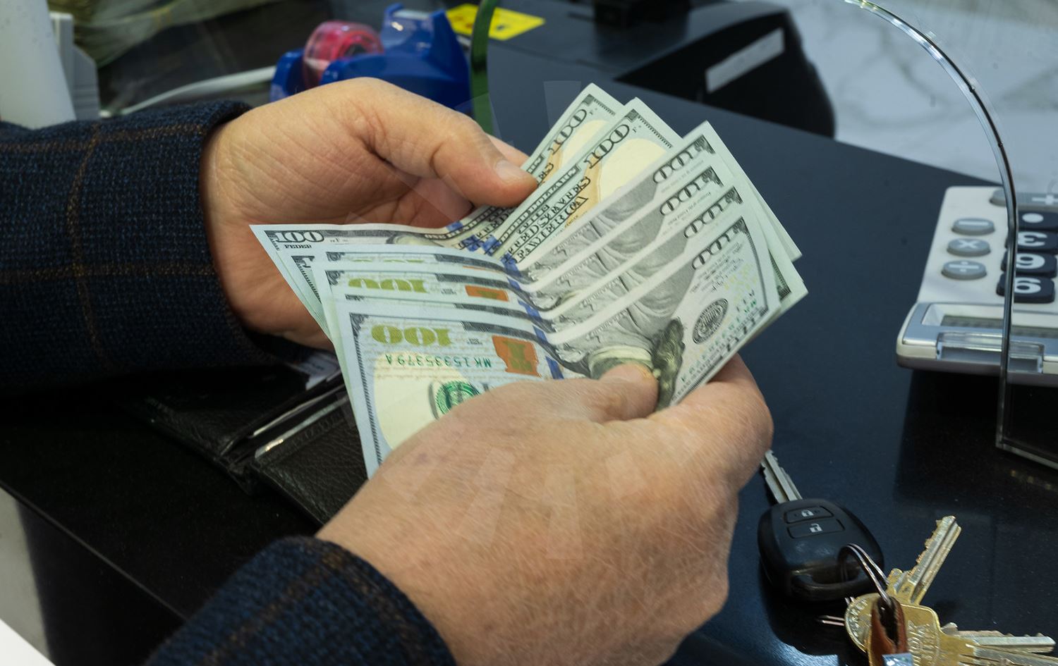 مبلغ من المال بعملة الدولار الأميركي بيد رجل