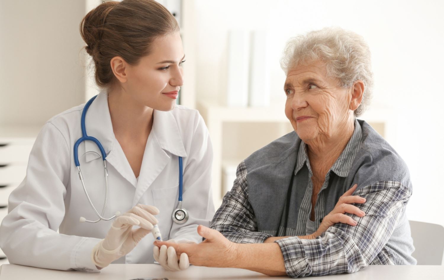 پزیشکێک پشکنینی شەکرە بۆ بەساڵاچوویەک دەکات.