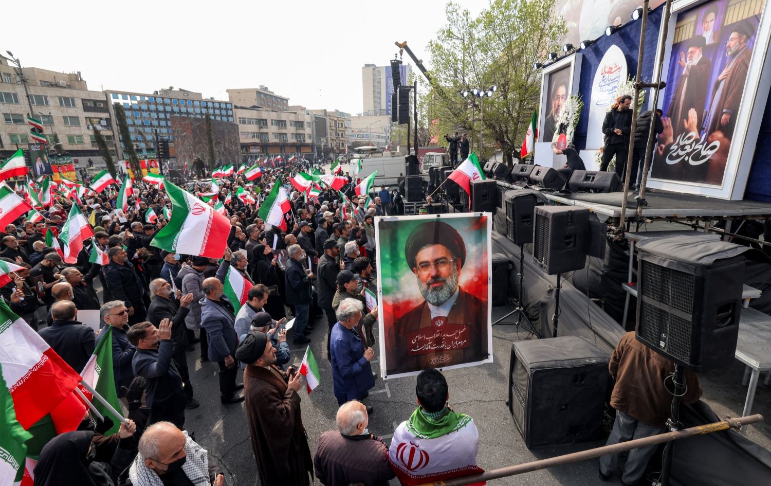 هاووڵاتییانی ئێران لە نێوەڕاستی تاران وێنەی موجتەبا خامنەیی، رێبەری نوێی کۆماری ئیسلامیی ئێرانیان هەڵگرتووە.وێنە: AFP