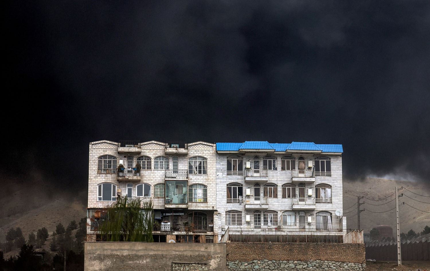 دووکەڵێکی رەشی چڕ ئاسمانی ناوچەیەکی تارانی تەنیوە دوای بۆردوومانی کۆگایەکی سووتەمەنی لەلایەن ئەمریکا و ئیسرائیلەوە. وێنە: AFP