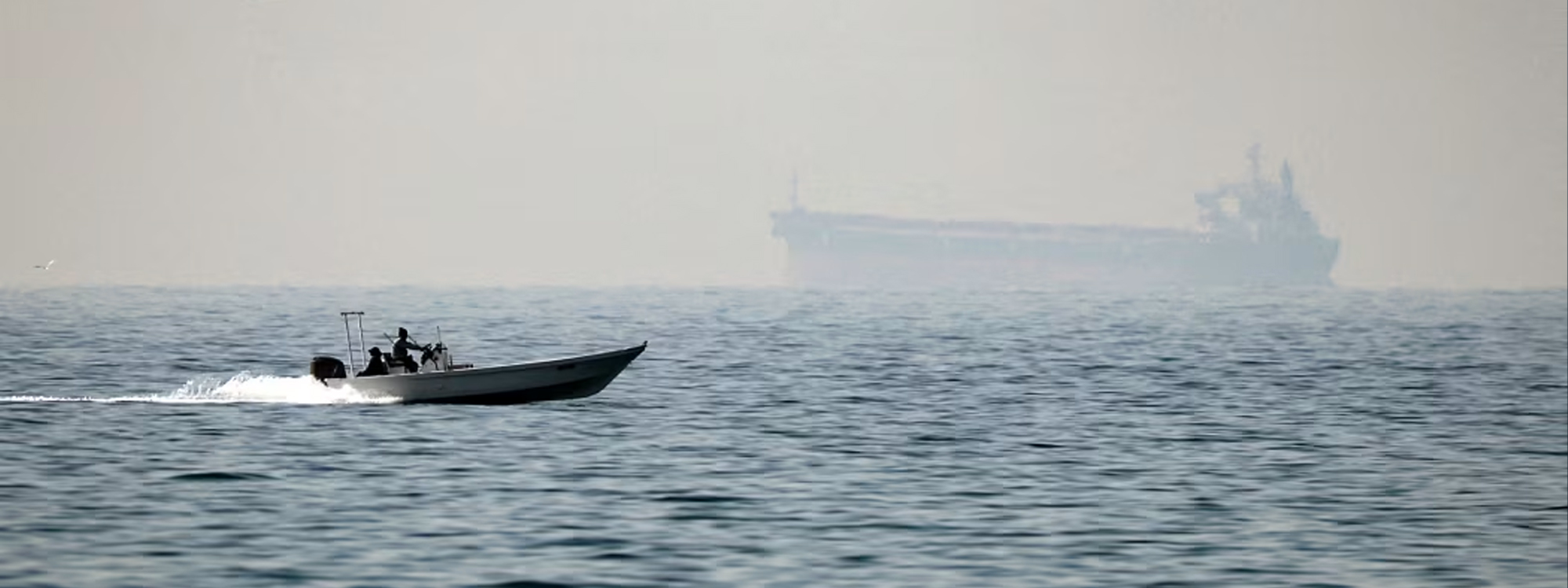 A motorboat cruises on the Strait of Hormuz with a tanker seen in the background, on February 25, 2026. Photo: Fadel Senna / AFP