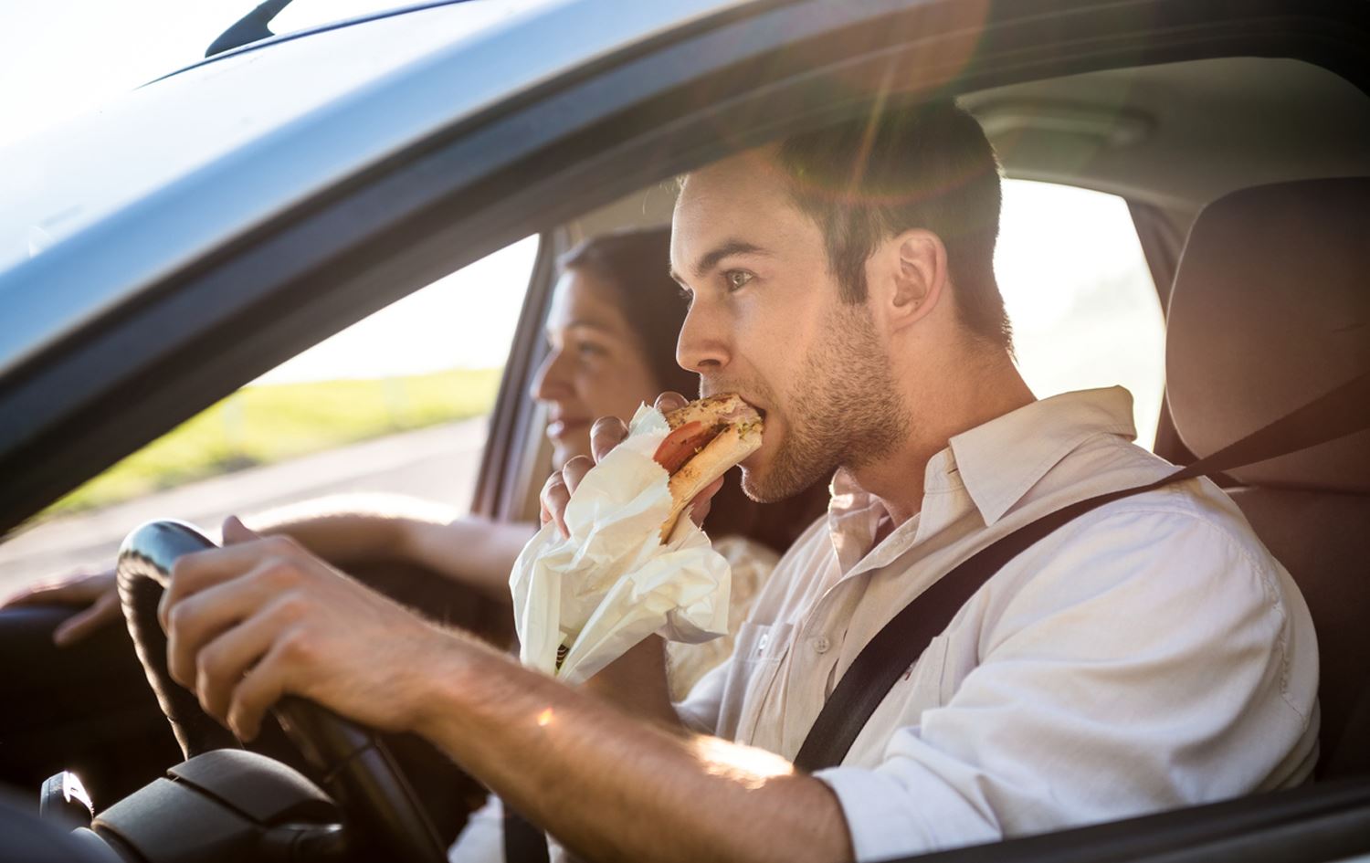 کەسێک لەکاتی شۆفێریدا خۆراک دەخوات. 