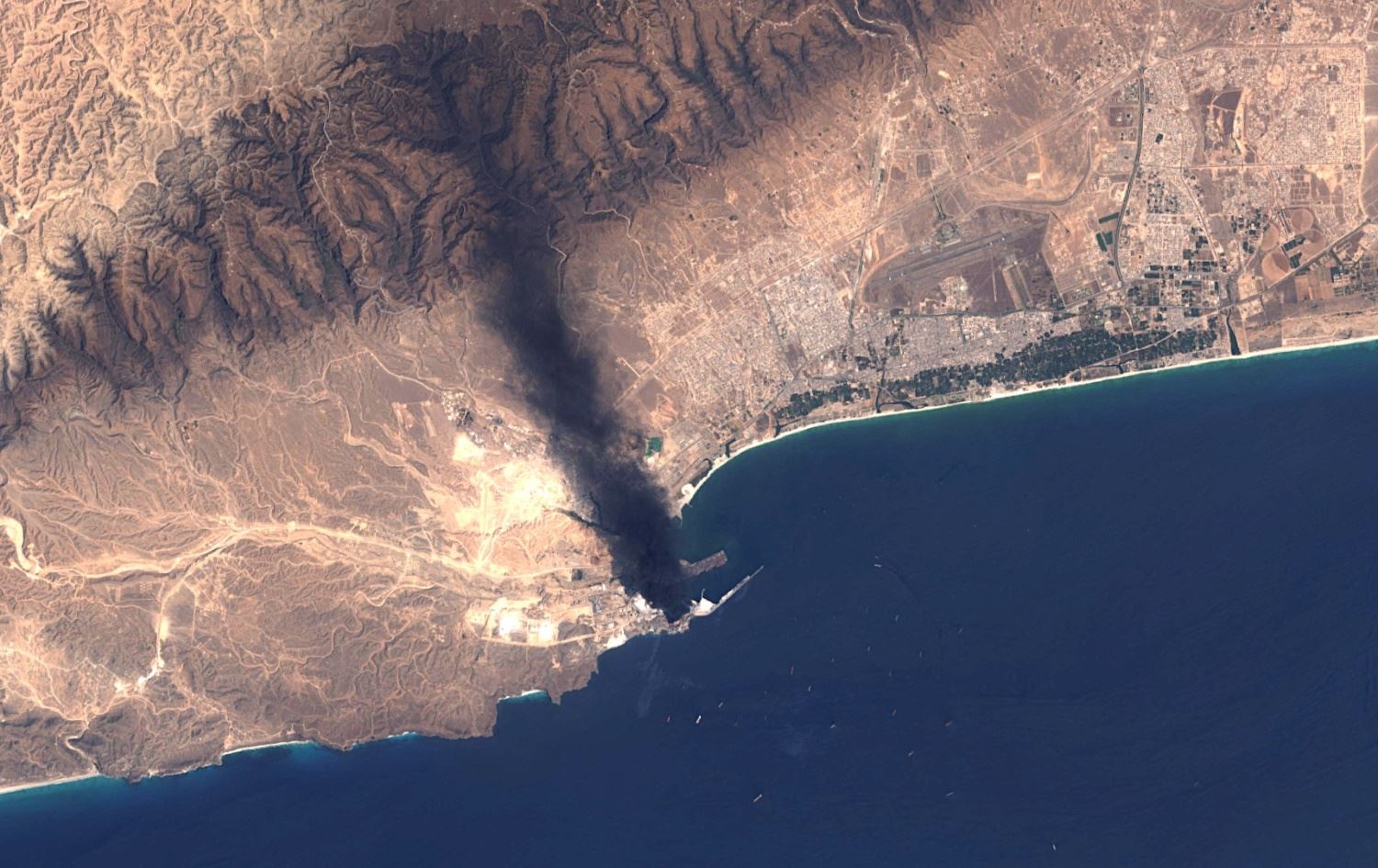 صورة أقمار صناعية تاحتها هيئة المسح الجيولوجي الأميركية تُظهر تصاعد الدخان من منشأة "مينا بتروليوم" في ميناء صلالة بسلطنة عُمان- AFP/ANDSAT-8/9 IMAGE COURTESY OF THE U.S. GEOLOGICAL SURVEY 