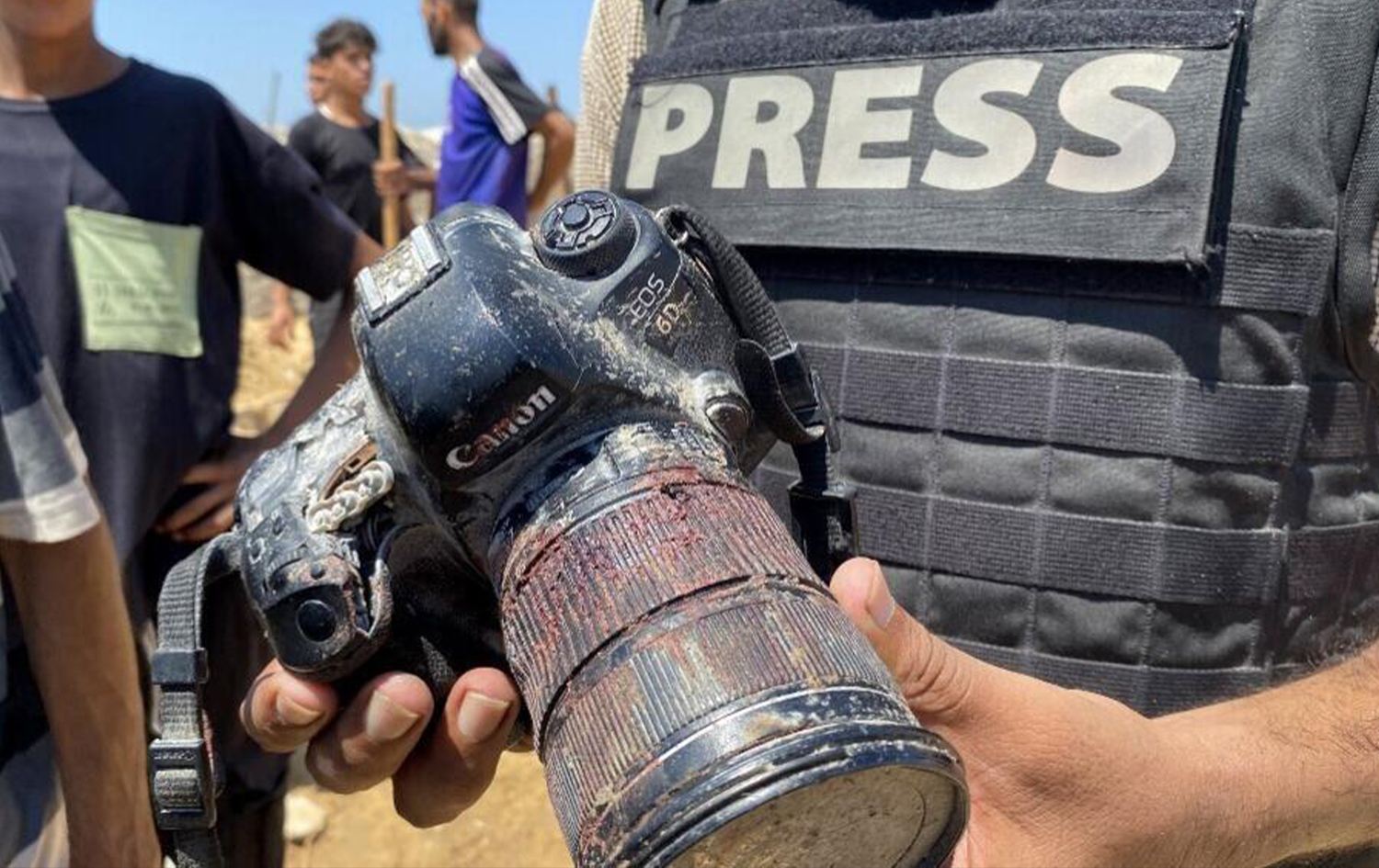 صحفي يحمل كاميرا ملطخة بالدماء تعود للمصورة الصحفية الفلسطينية مريم دقة، التي قُتلت في غارة إسرائيلية على مستشفى ناصر في خان يونس جنوب قطاع غزة، خلال جنازتها في 25 آب 2025. AFP