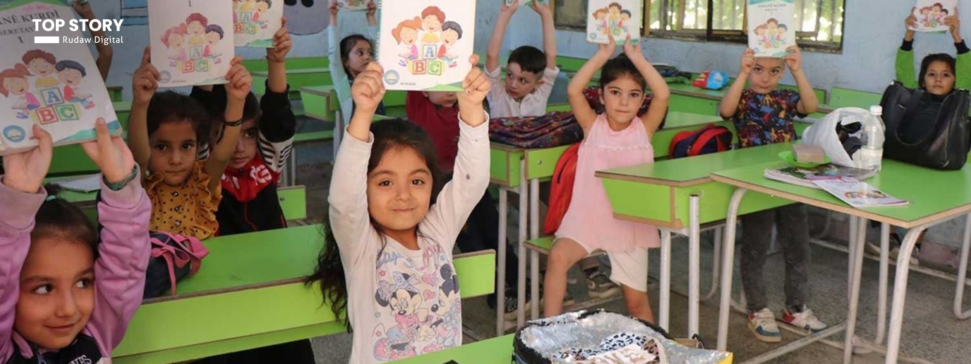 Students hold up Kurdish language books in a class in Rojava. Photo: ANHA/file